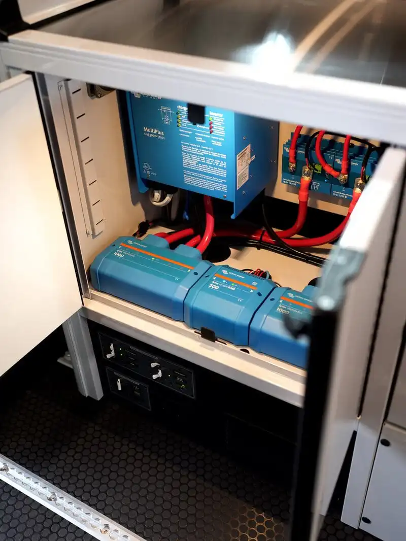 dsc06516 - Patrol Vans - Patrol Vans Open electrical cabinet showing blue modular power modules connected by red battery cables and wiring inside a maintenance rack